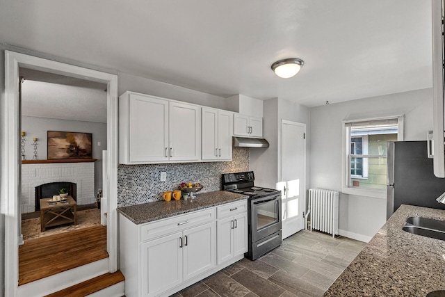 kitchen featuring stainless steel refrigerator, white cabinetry, electric range, radiator heating unit, and dark stone counters