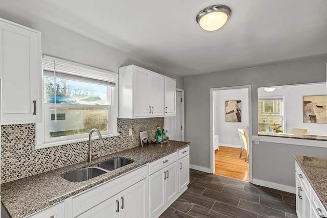 kitchen with tasteful backsplash, dark wood-type flooring, sink, dark stone countertops, and white cabinetry