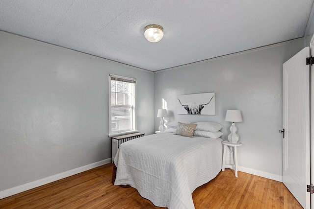 bedroom with radiator, crown molding, a textured ceiling, and hardwood / wood-style flooring