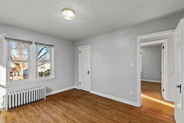 unfurnished room with radiator, a textured ceiling, and hardwood / wood-style flooring