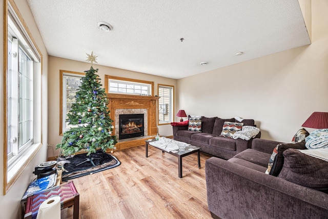 living room with wood-type flooring, a textured ceiling, a wealth of natural light, and a premium fireplace