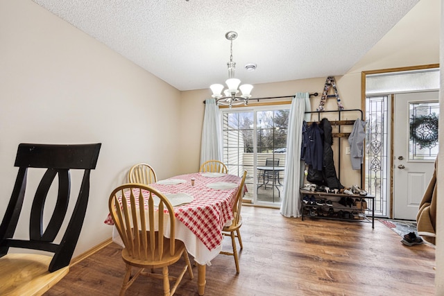 dining room with a textured ceiling, vaulted ceiling, a notable chandelier, and hardwood / wood-style flooring