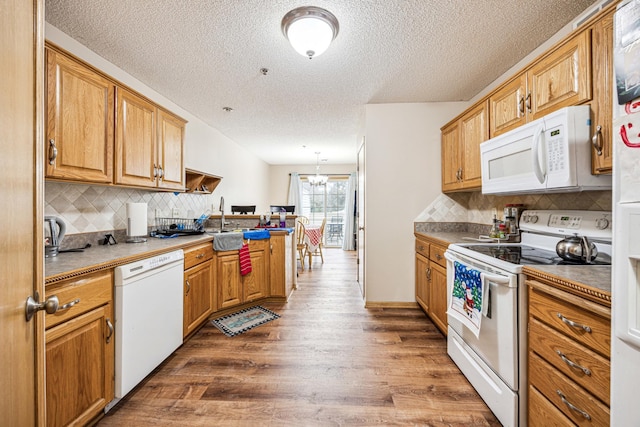 kitchen featuring a textured ceiling, dark hardwood / wood-style floors, white appliances, and a notable chandelier