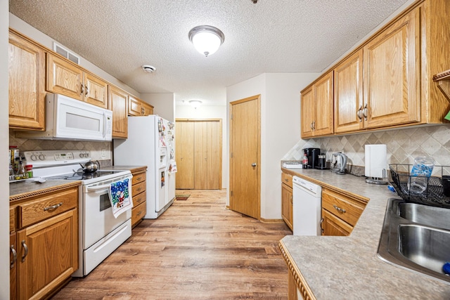 kitchen featuring white appliances, sink, light hardwood / wood-style flooring, a textured ceiling, and tasteful backsplash