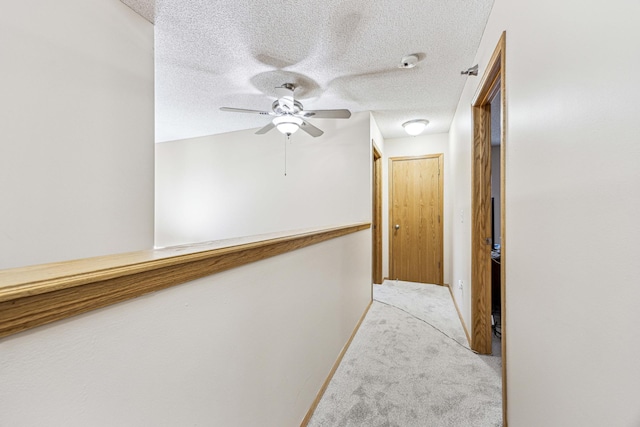 corridor featuring light carpet and a textured ceiling