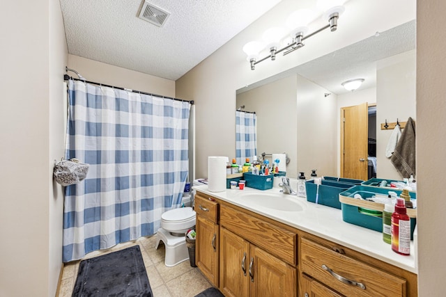 bathroom with tile patterned floors, vanity, a textured ceiling, and toilet