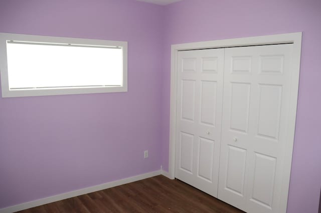 unfurnished bedroom with a closet and dark wood-type flooring