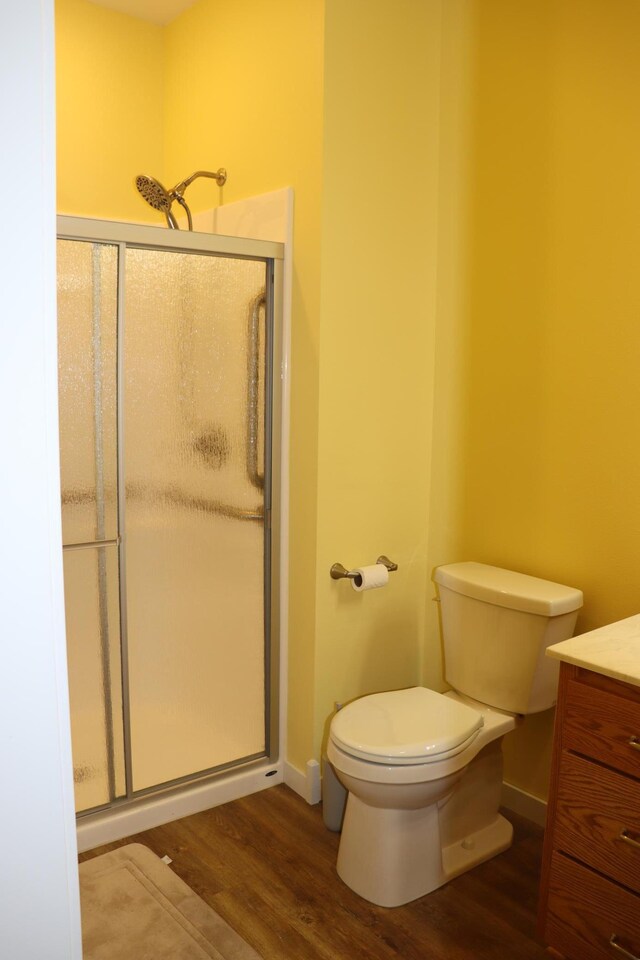 bathroom with toilet, an enclosed shower, wood-type flooring, and vanity