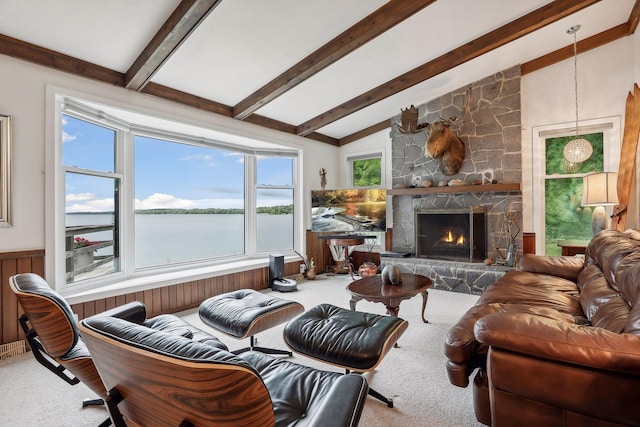 living room with carpet floors, a stone fireplace, a water view, and vaulted ceiling with beams