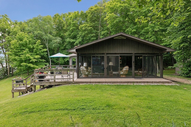 rear view of house featuring a lawn and a wooden deck