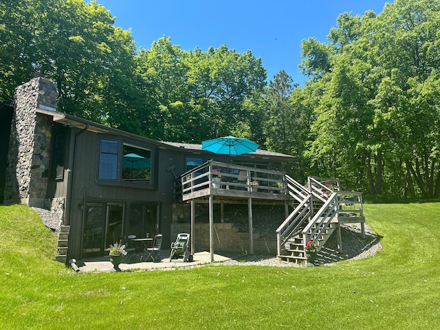 back of property with a lawn, a deck, and a patio