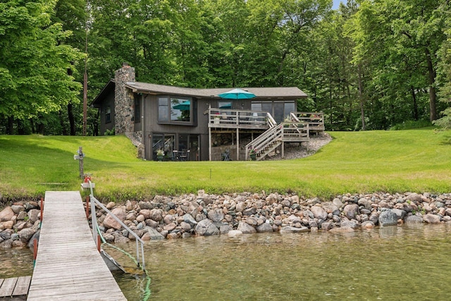 rear view of house with a yard and a deck with water view