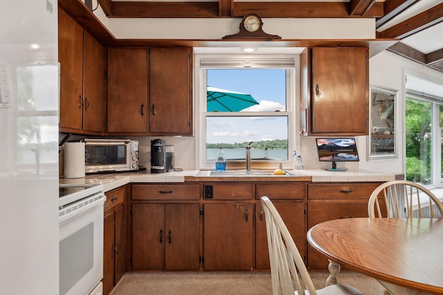 kitchen with tasteful backsplash, stove, white refrigerator, and sink