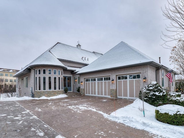 view of front of house with an attached garage, stone siding, and stucco siding