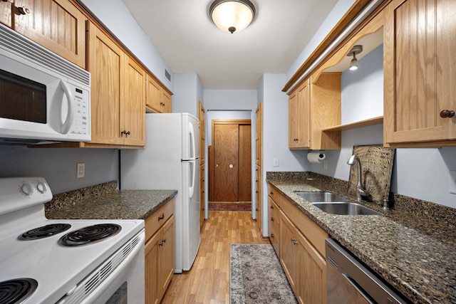 kitchen with dark stone counters, sink, light hardwood / wood-style floors, and white appliances