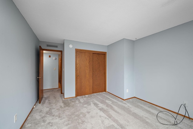 unfurnished bedroom featuring light carpet and a closet