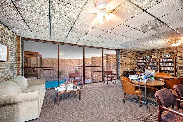 interior space with a drop ceiling and brick wall