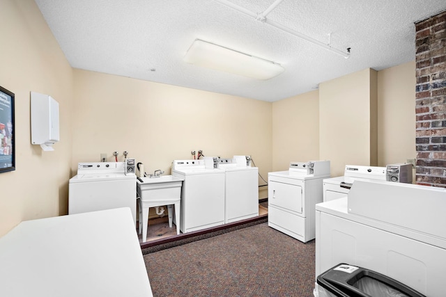 laundry area featuring a textured ceiling, dark carpet, and washing machine and clothes dryer