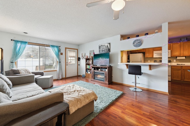 living room with hardwood / wood-style floors, a textured ceiling, and ceiling fan