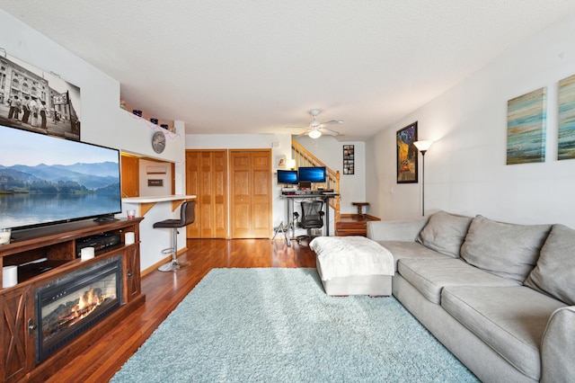 living room with a textured ceiling, ceiling fan, and dark hardwood / wood-style floors