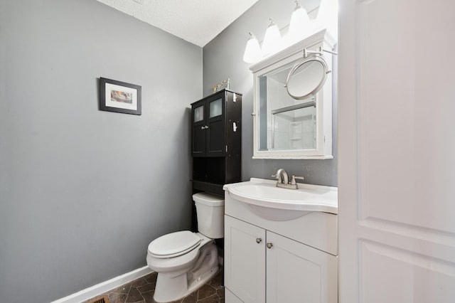 bathroom with a textured ceiling, vanity, and toilet