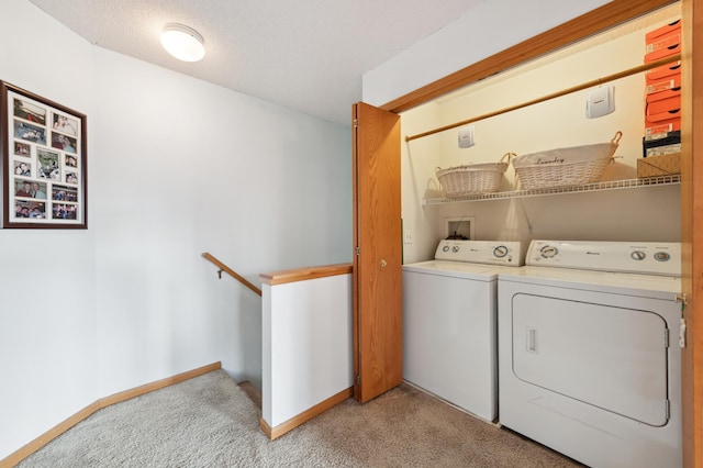 clothes washing area featuring a textured ceiling, light colored carpet, and washing machine and clothes dryer