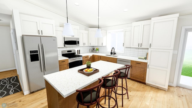 kitchen with a center island, sink, stainless steel appliances, pendant lighting, and light hardwood / wood-style floors