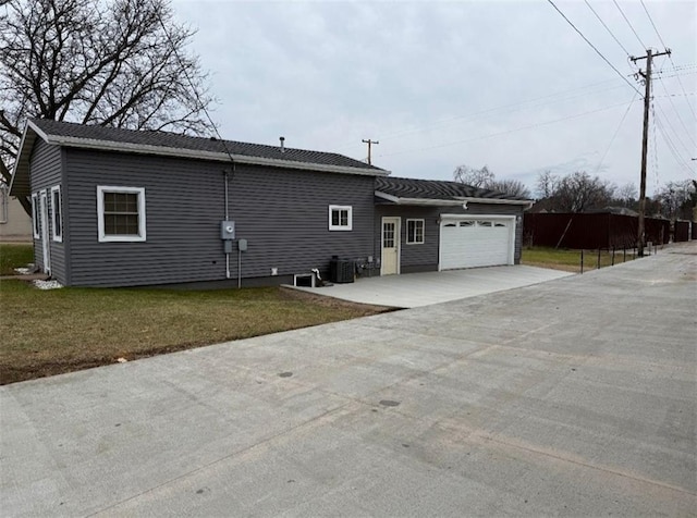 exterior space with a garage, central air condition unit, and a yard