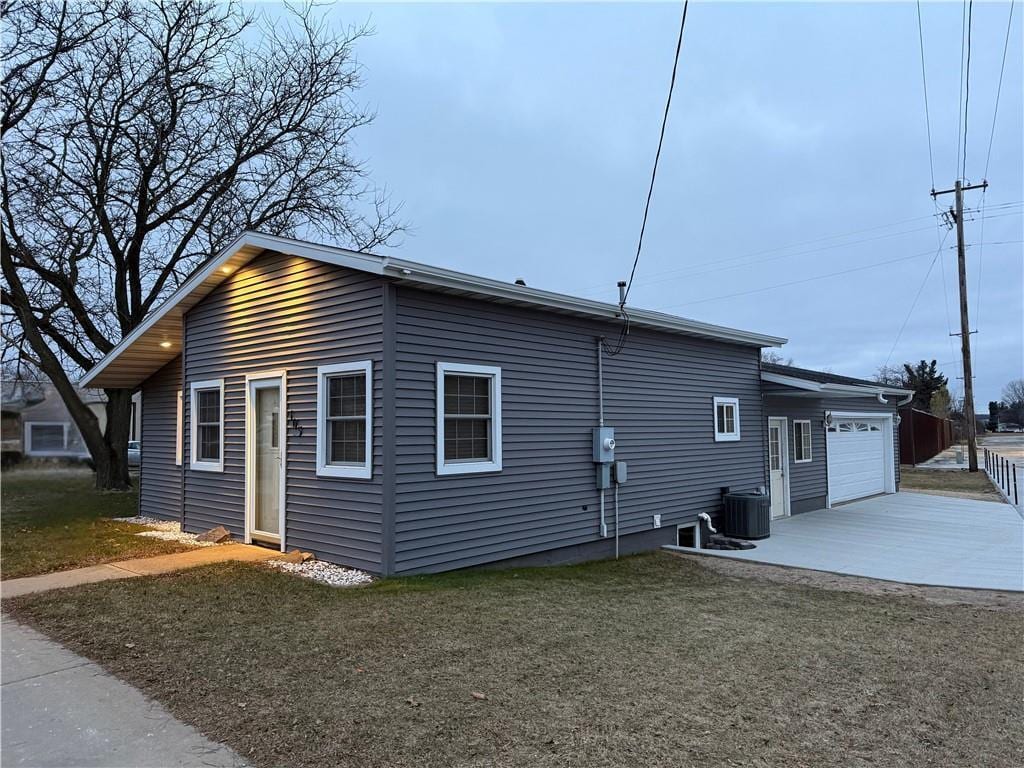 view of side of property featuring cooling unit, a garage, and a yard