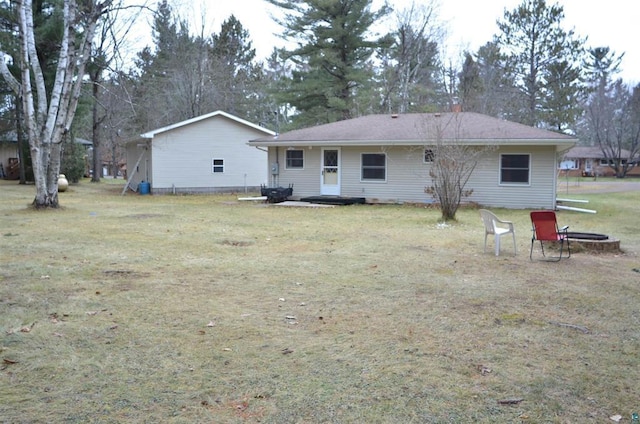 rear view of property with a lawn and a fire pit