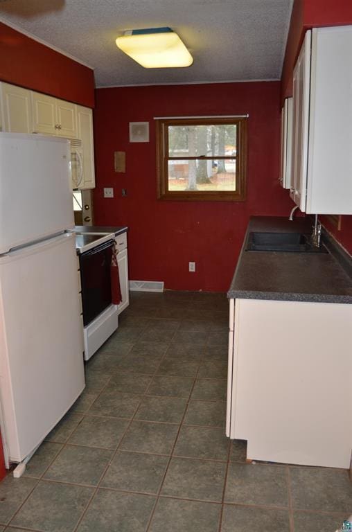 kitchen featuring white cabinetry, sink, dark tile patterned flooring, and white appliances