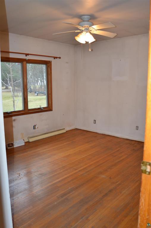 spare room featuring ceiling fan, wood-type flooring, and a baseboard radiator