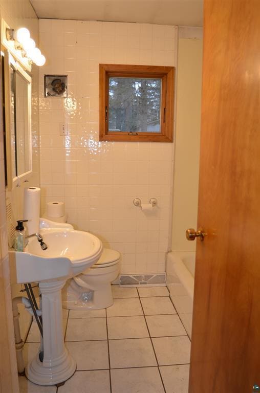 bathroom featuring tile patterned floors, tile walls, and toilet