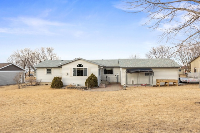 rear view of property featuring a shingled roof and a yard