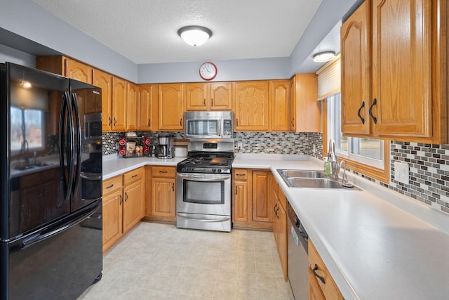 kitchen with stainless steel appliances, backsplash, a sink, and light countertops