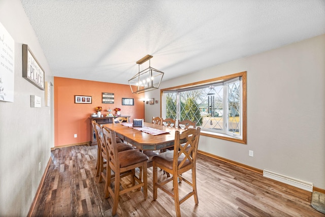 dining area featuring baseboards, a textured ceiling, visible vents, and wood finished floors