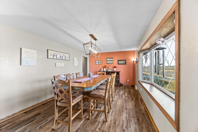 dining space with a textured ceiling, dark wood finished floors, and baseboards