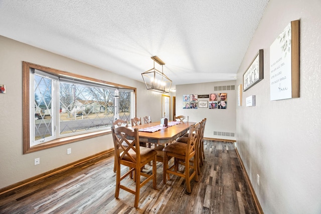 dining room featuring dark wood-style floors, visible vents, and a textured ceiling