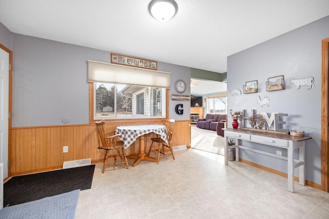 dining space with visible vents, wainscoting, wood walls, a textured ceiling, and tile patterned floors