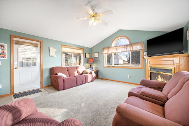 carpeted living room with baseboards, vaulted ceiling, a ceiling fan, and a glass covered fireplace