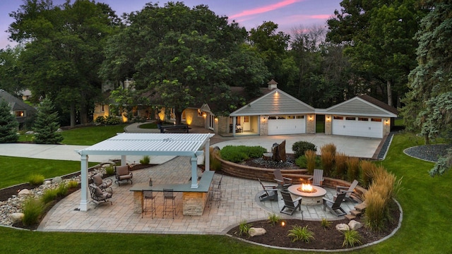 back house at dusk with an outdoor fire pit, an outdoor bar, a patio area, and a lawn