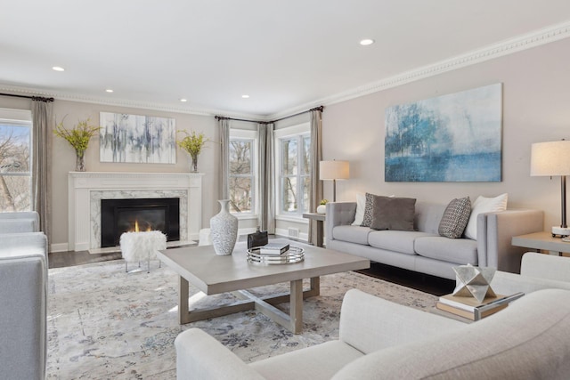 living room with a high end fireplace, ornamental molding, and light wood-type flooring