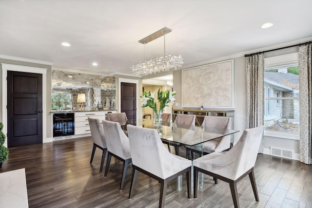 dining space with dark hardwood / wood-style flooring, ornamental molding, beverage cooler, and bar area