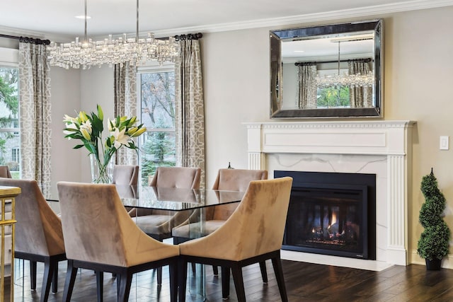 dining space with an inviting chandelier, crown molding, a fireplace, and dark hardwood / wood-style floors