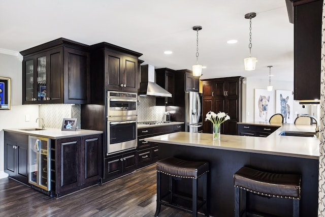 kitchen featuring pendant lighting, decorative backsplash, stainless steel appliances, and wall chimney exhaust hood