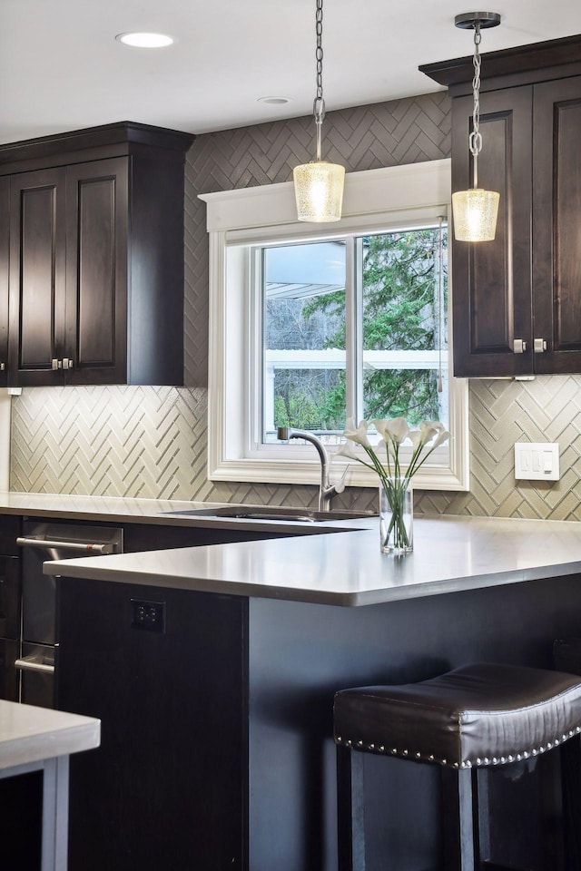 kitchen with dark brown cabinets, sink, hanging light fixtures, and backsplash