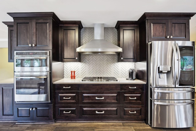 kitchen with appliances with stainless steel finishes, dark wood-type flooring, wall chimney range hood, and decorative backsplash