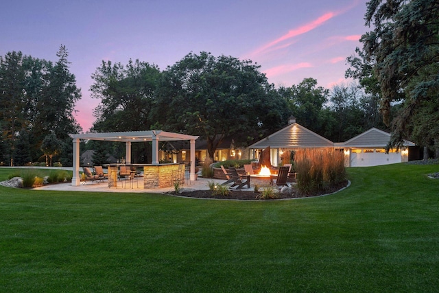 yard at dusk featuring a patio area, an outdoor bar, and an outdoor fire pit