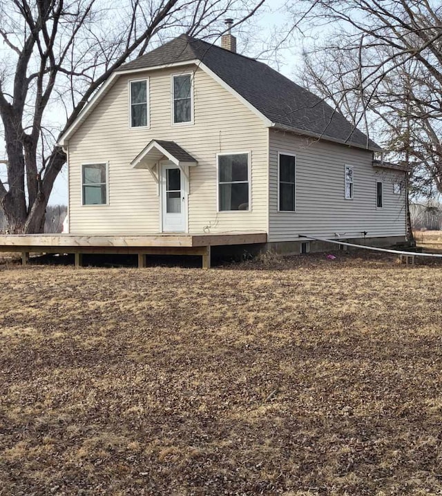 back of property featuring a shingled roof, a wooden deck, and a chimney