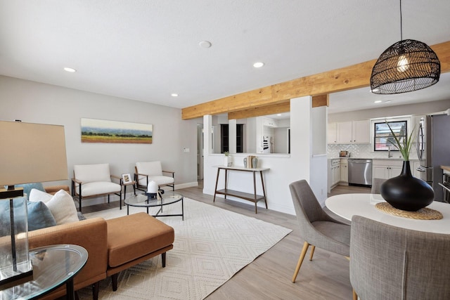 living room featuring beamed ceiling and light wood-type flooring